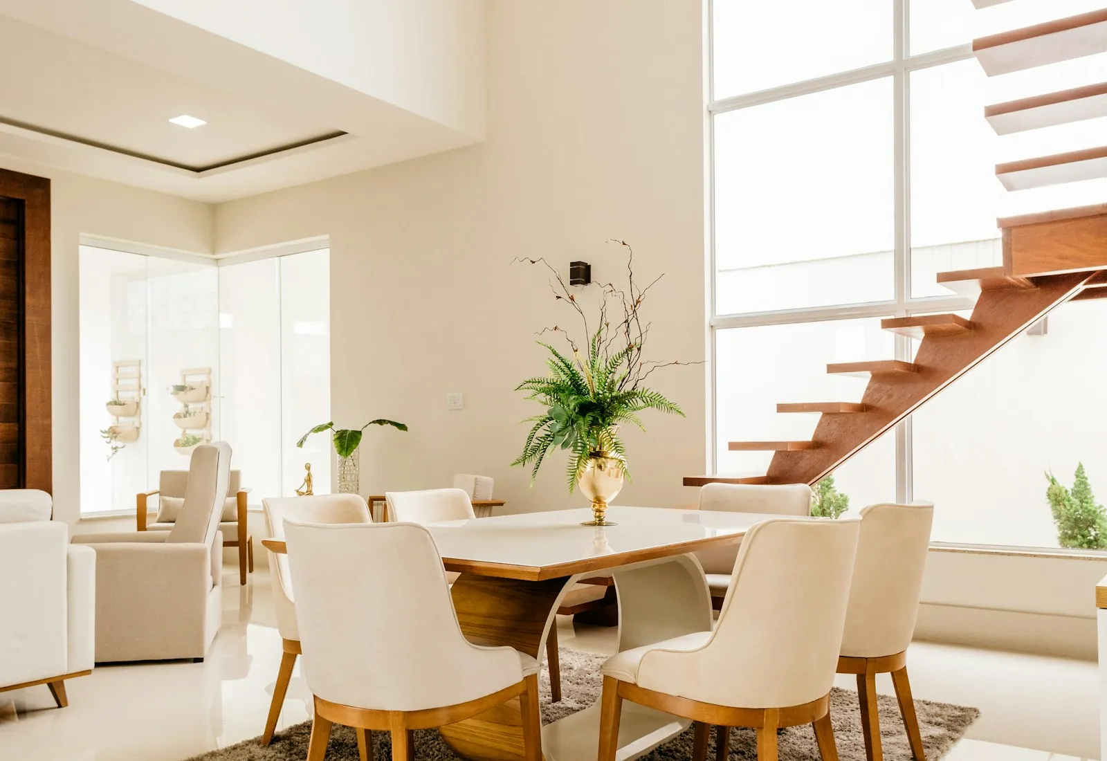 Interior de casa contemporânea com pé-direito duplo, escada suspensa e sala de jantar